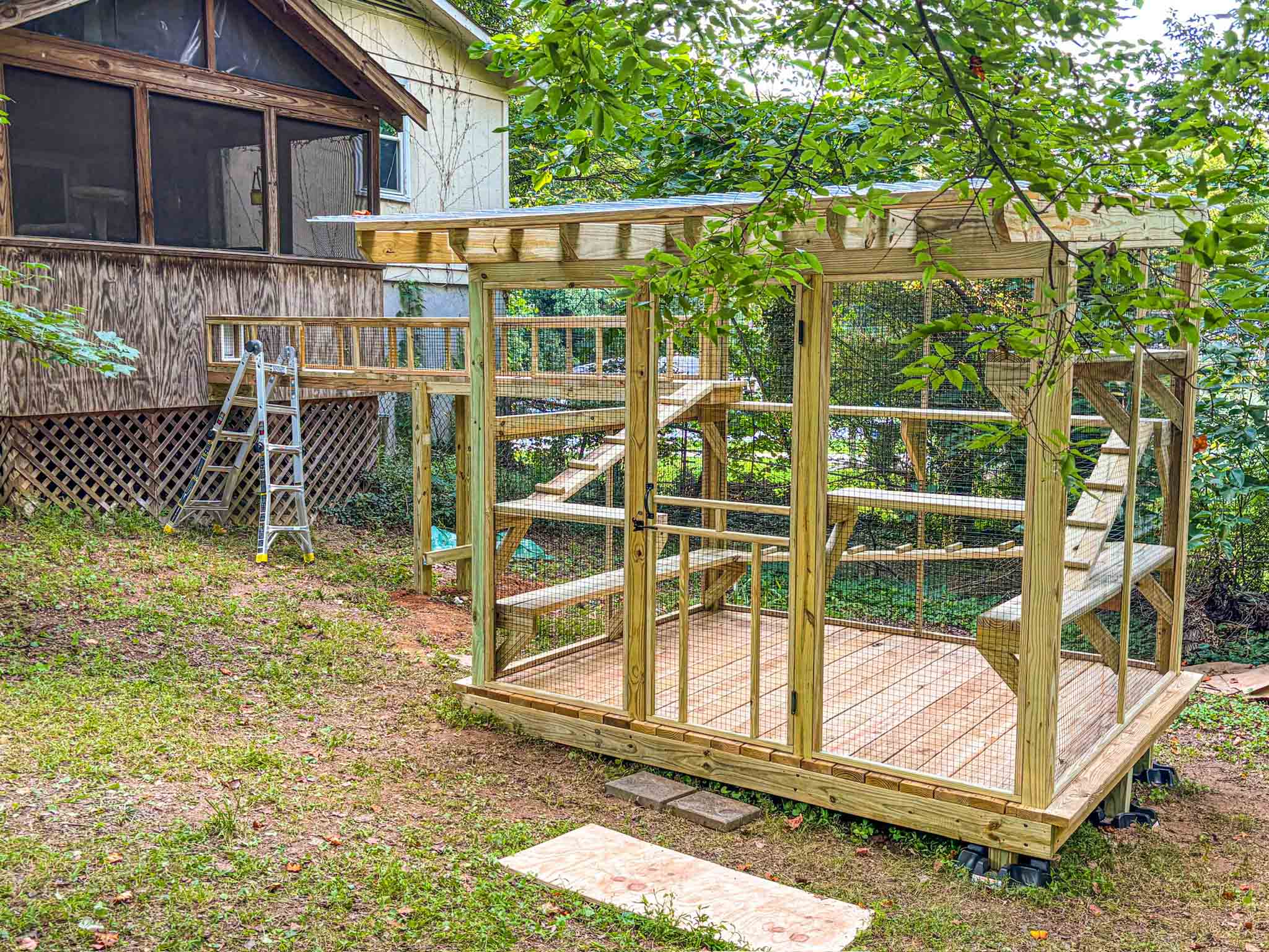 Large custom outdoor catio with elevated platforms and a tunnel connected to a screened porch.