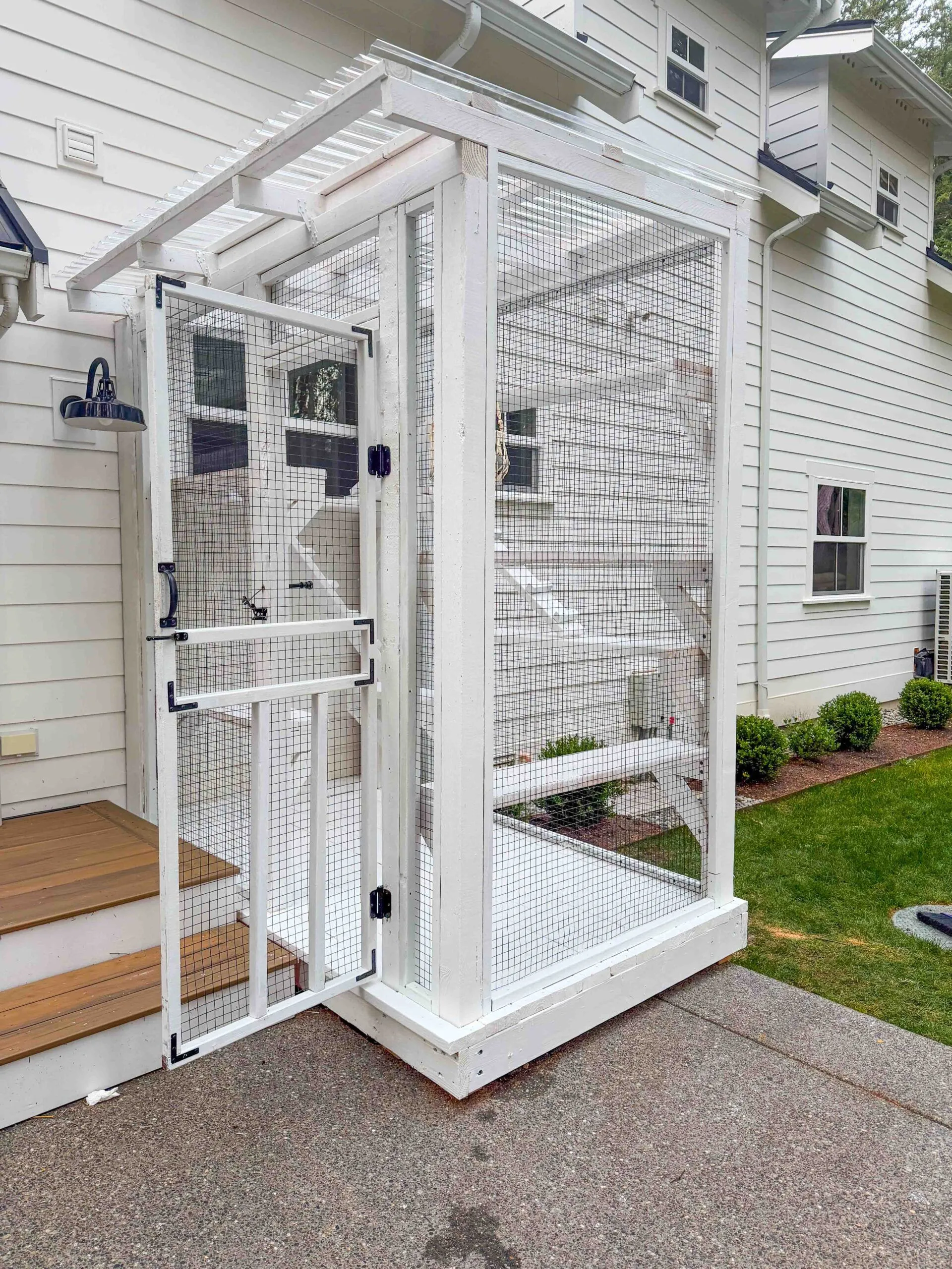 White catio with open door leading from the porch to an enclosed climbing space for cats.