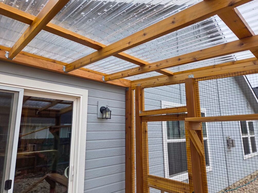 Close-up of catio roof connection and mesh framing above sliding door.
