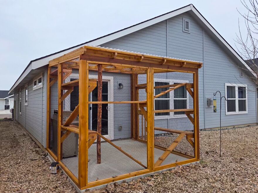 Full view of attached catio along side of house with cedar structure and multiple platforms.