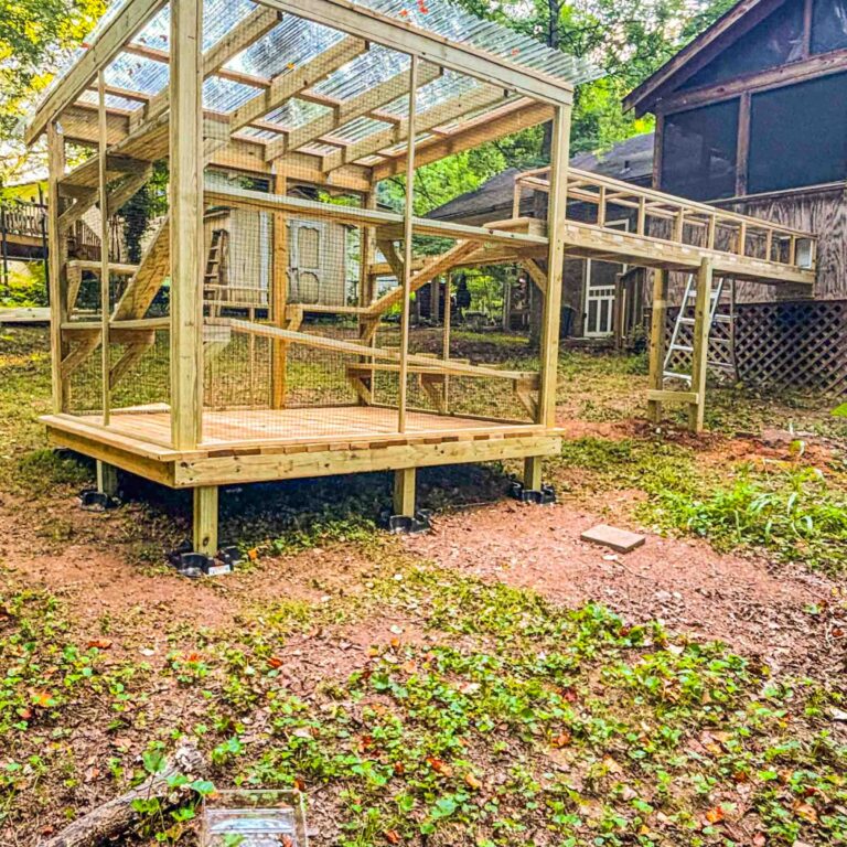 Raised open-frame catio under construction in a wooded yard