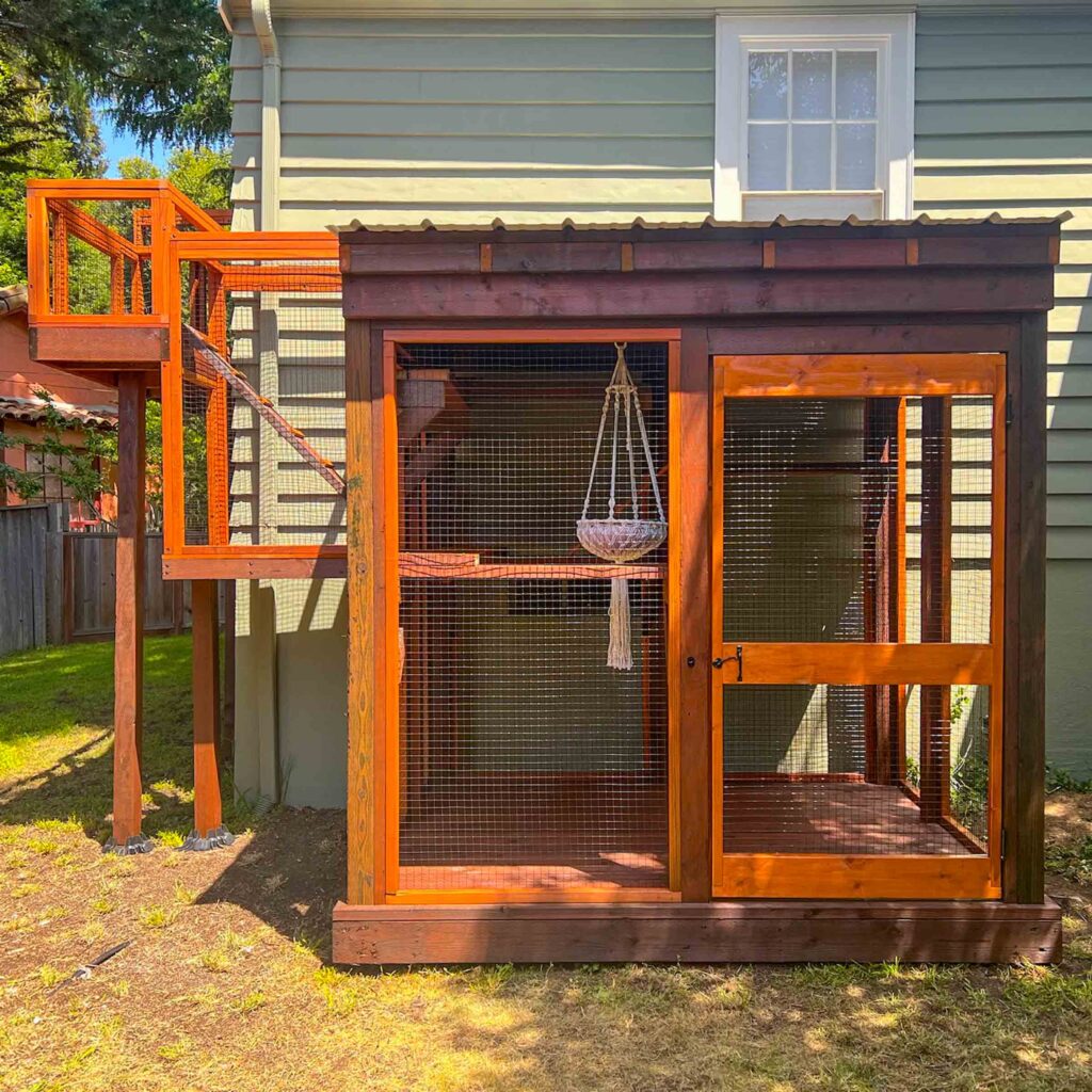 Elevated redwood catio with tunnel connecting to second story window and multi-level outdoor enclosure
