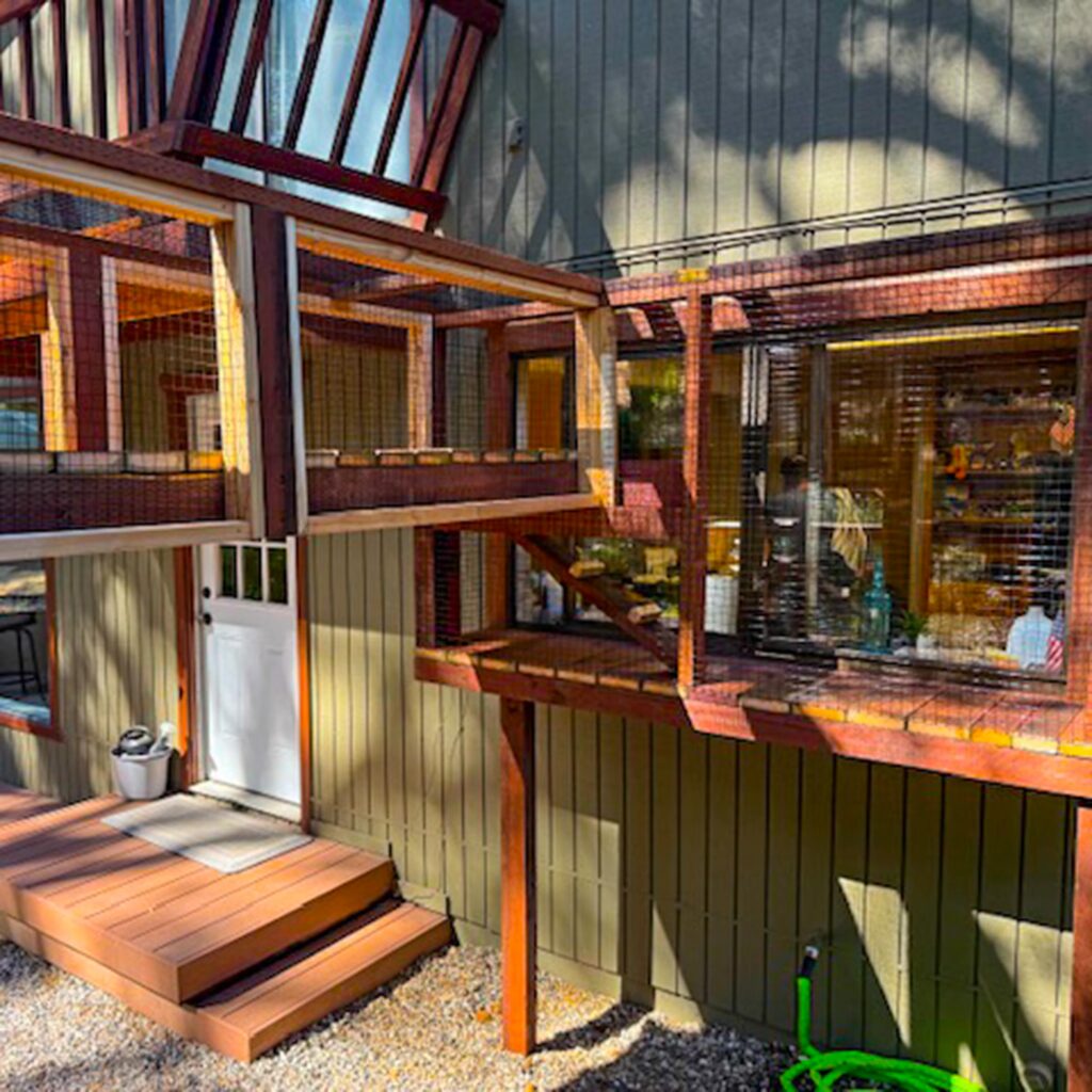 Elevated catio with enclosed walkways attached to house windows and outdoor deck