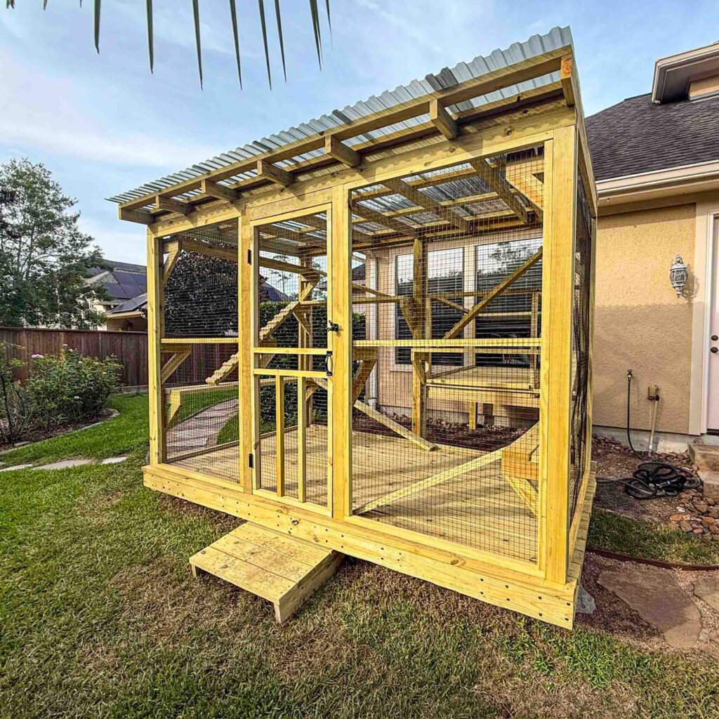 Spacious backyard catio with natural wood frame, mesh siding, and metal roof attached to home exterior