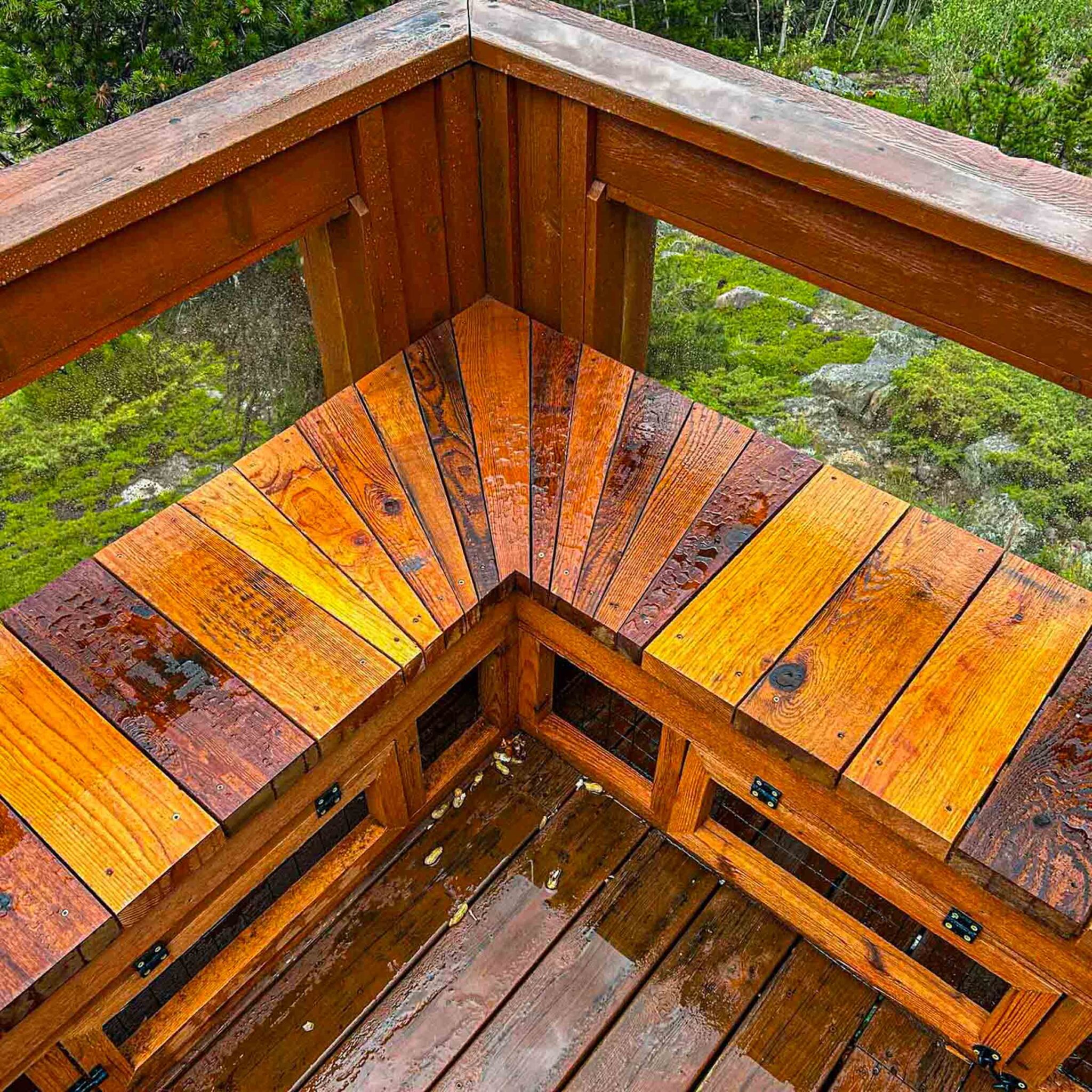 A close-up view of a wooden catio corner bench with slatted seating and built-in ventilation panels.