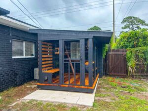 Backyard custom catio with black framing and wood details connected to a house.