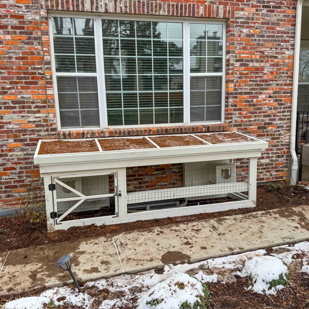 Compact white window catio with wire mesh, designed for winter safety.