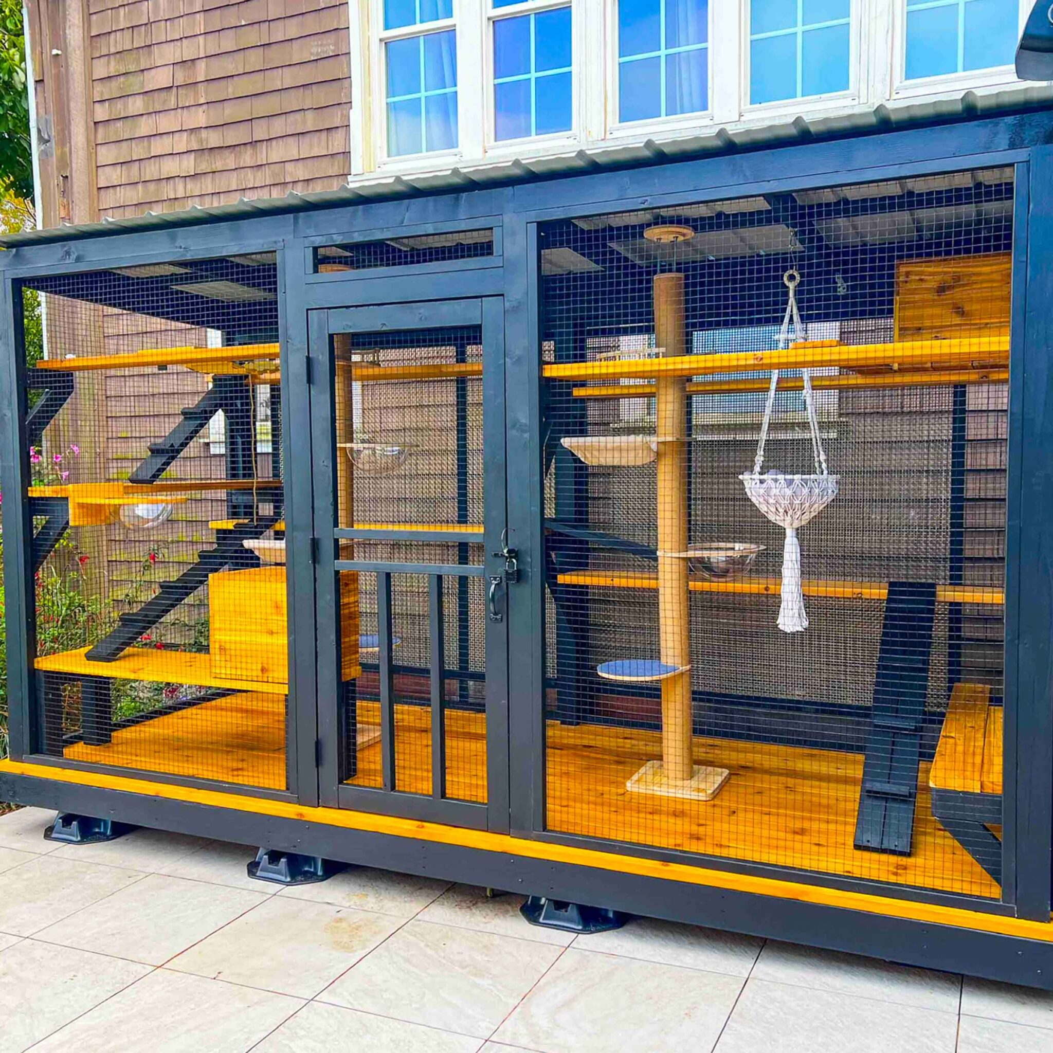 Large enclosed outdoor catio attached to a home, featuring ramps, bubble beds, and a hanging hammock.