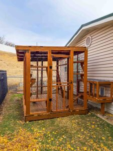Exterior view of a large wooden catio attached to a home in Lowden, Washington, with secure wire mesh walls and an entry door for easy access.