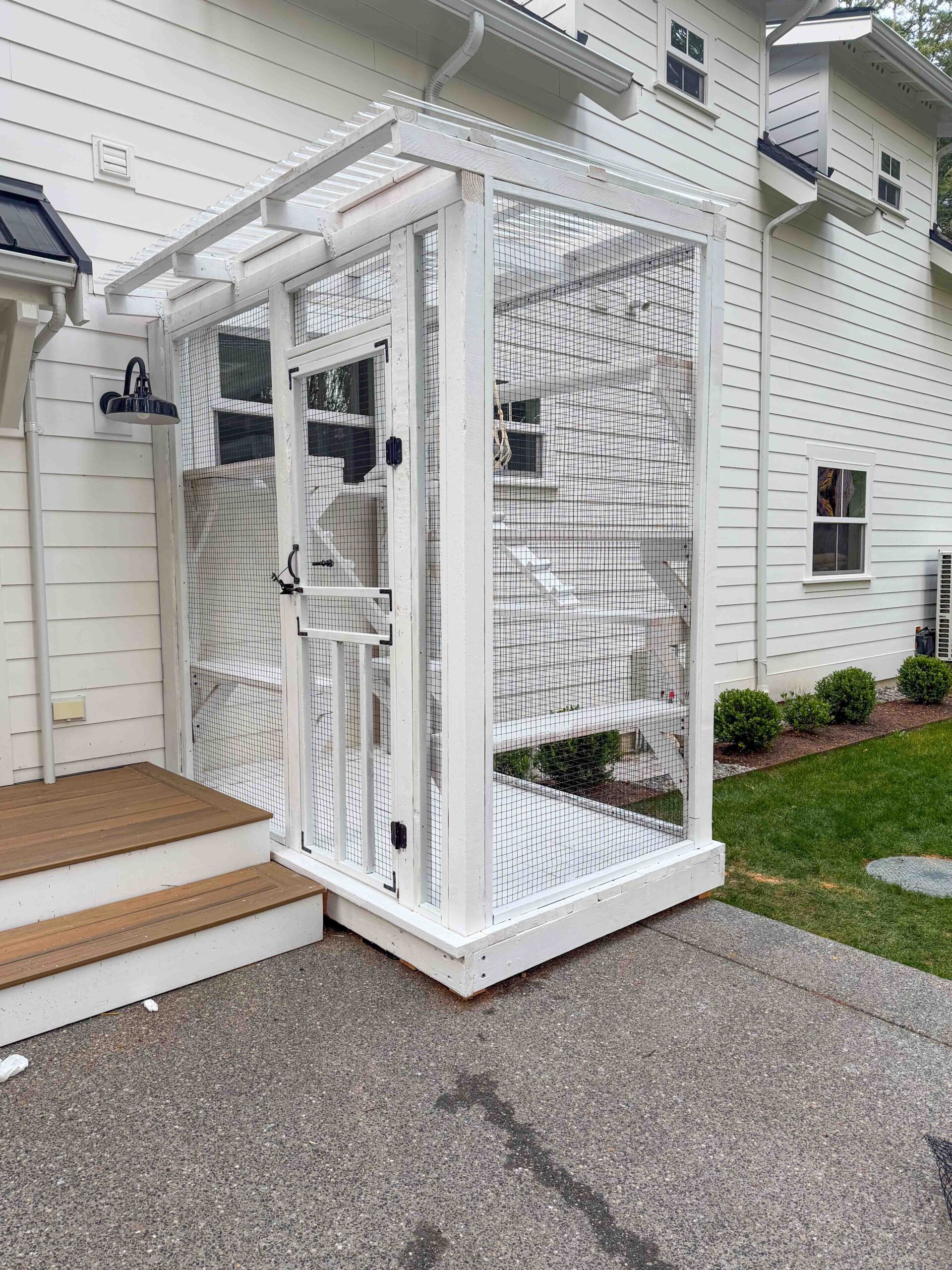 Custom white catio connected to a back porch with clear roof panels and secure mesh walls.