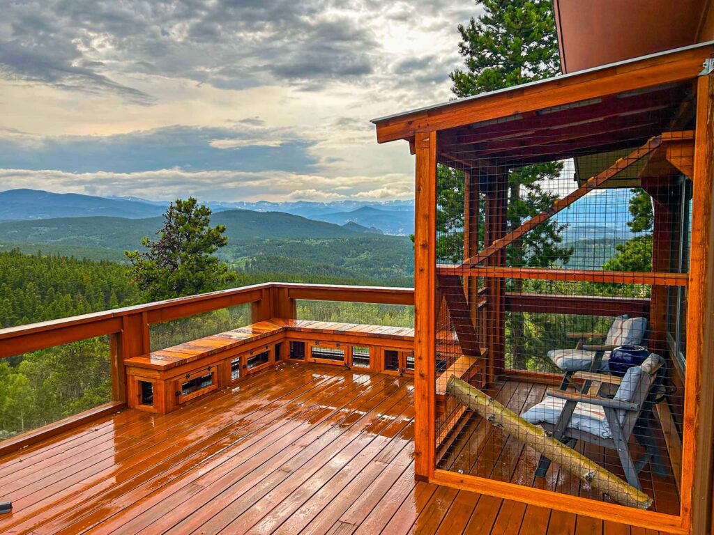 Custom wooden deck-adjacent catio with mountain views and enclosed climbing platforms.