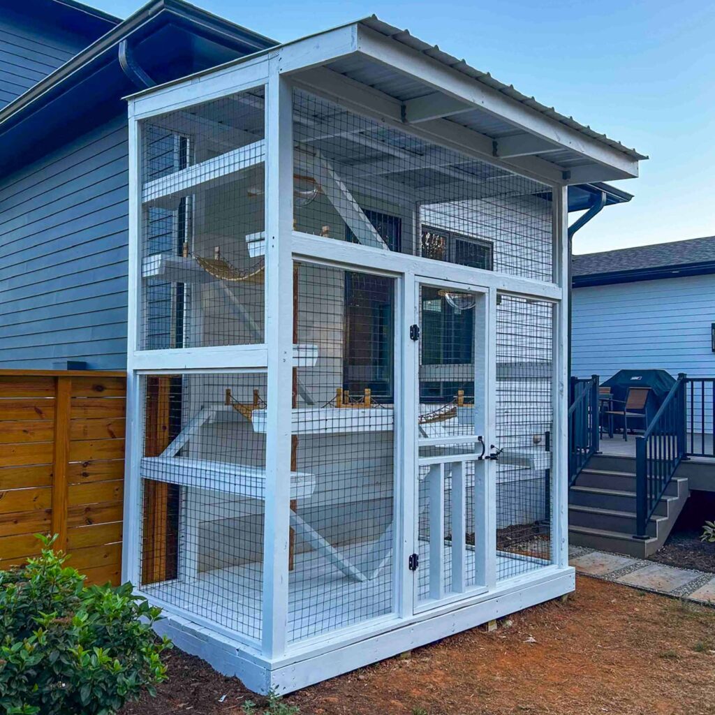 Large white outdoor catio attached to a house with multiple levels and enclosed wire panels.