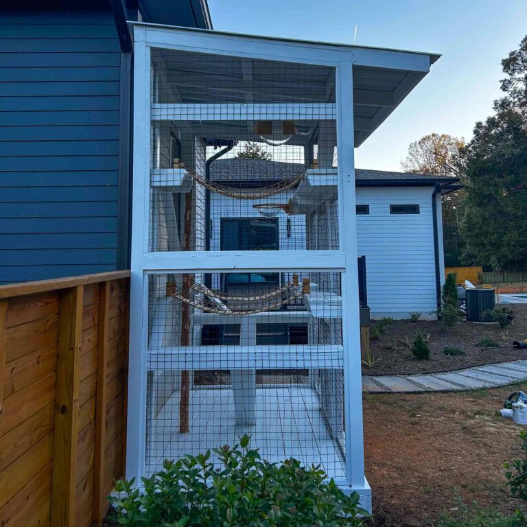 Tall white catio viewed from the side, featuring stacked shelves and a rope bridge inside the enclosure.