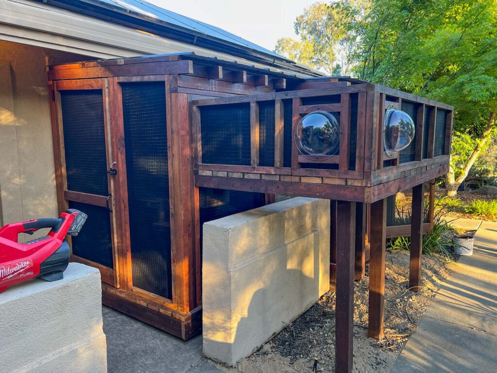 Elevated wooden catio with bubble windows and an extended enclosed walkway.