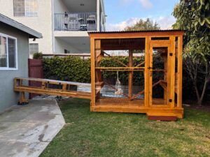 Full backyard view of a large custom cedar catio with corrugated metal roof, multi-level platforms, secure mesh walls, and attached access tunnel from the home.