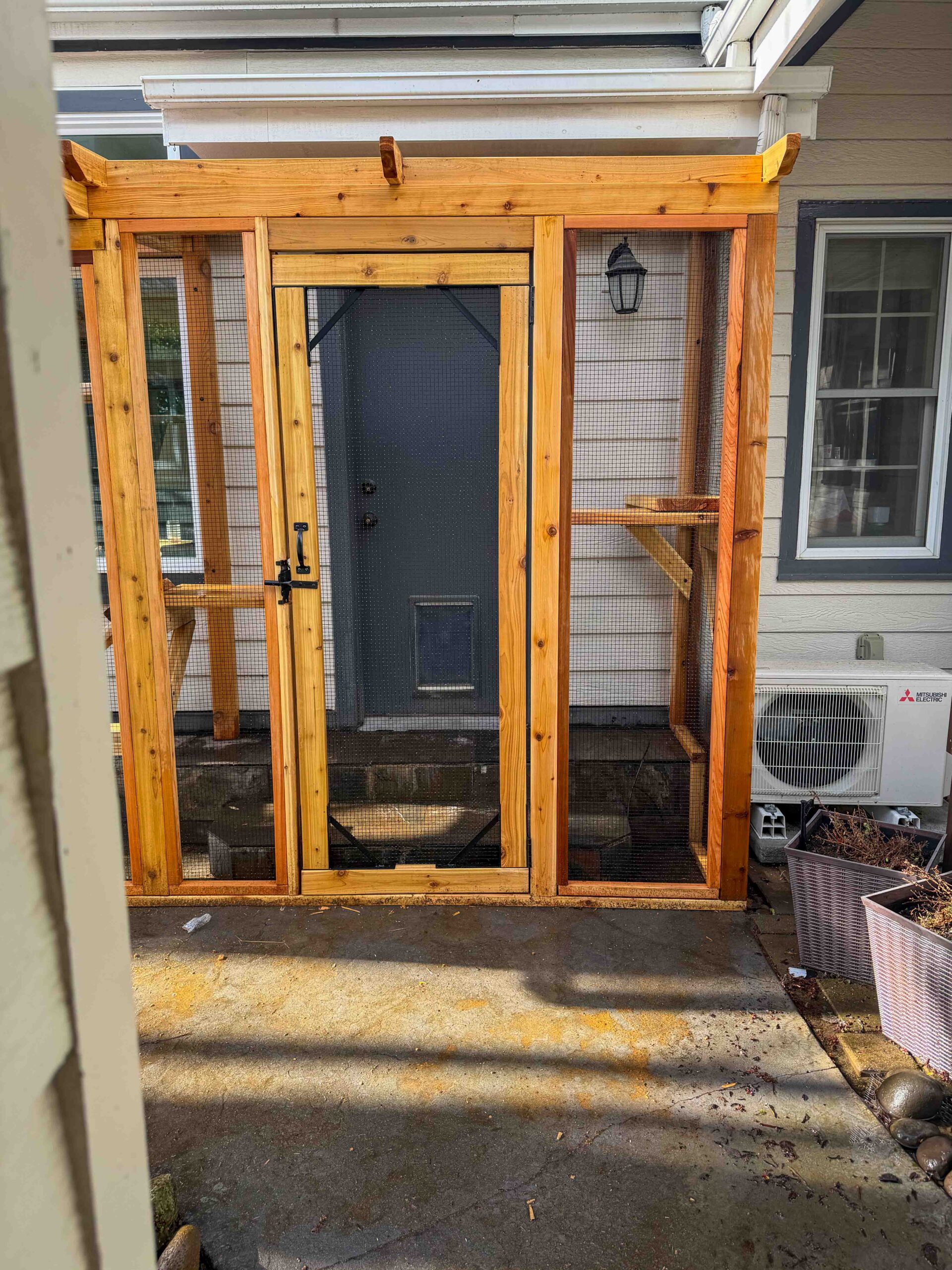 Front view of a custom catio door with a secure latch system and wire mesh panels, providing safe outdoor access for cats directly from the home.